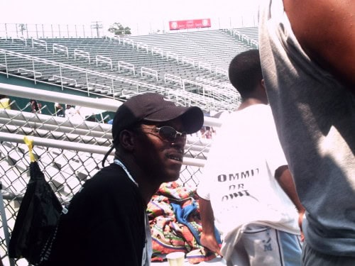 Coach with athletes at Panthers Elite Track & Field meet in stadium stands.
