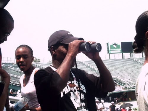 Young athlete using binoculars at Panthers Elite Track & Field event.