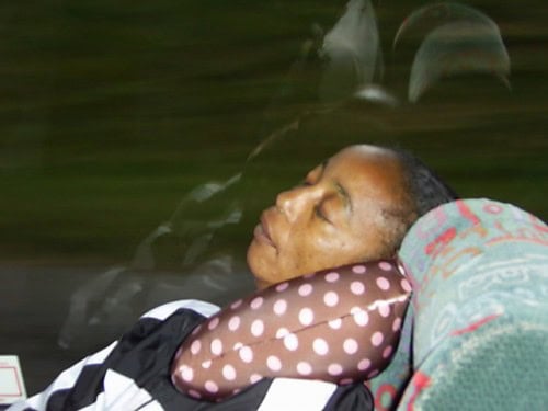 Relaxed woman resting with a polka dot pillow on a bus or train.
