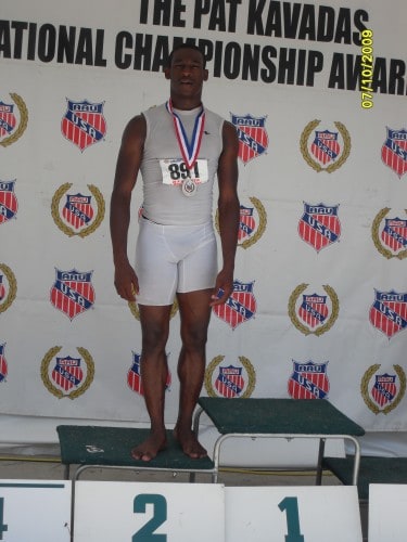 Young male athlete on podium with medal at Panthers Elite Track & Field event.