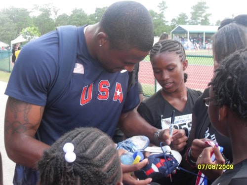 A vibrant group of young athletes receiving coaching and support at a track and field event.