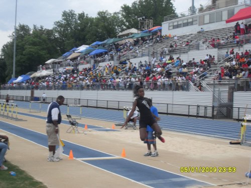 Panthers Elite Track & Field athletes competing at an outdoor stadium with spectators in the stands.