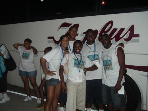 A vibrant group of young athletes smiling in front of a Panthers Elite Track & Field bus.