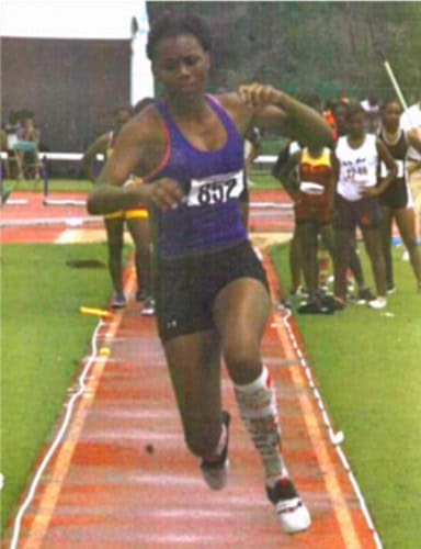 Elite female sprinter running on a track during a competition.