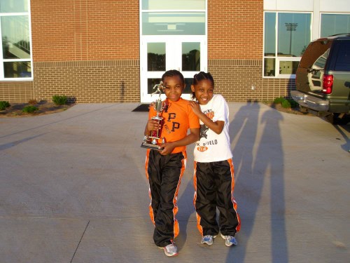 Two young female athletes holding a trophy outside Panthers Elite Track & Field Club.
