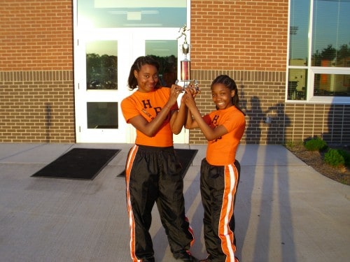 Two young female athletes holding a trophy outside Panthers Elite Track & Field Club.
