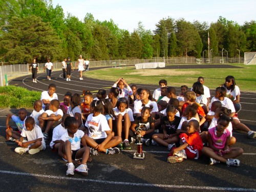 Youth track and field team sitting on the track at Panthers Elite Track & Field Club.