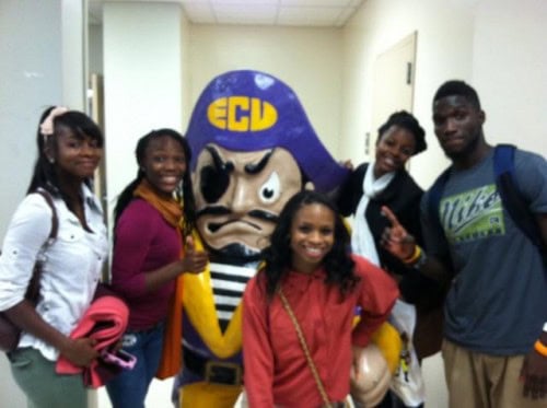 Young athletes with Panthers Elite team and mascot at school hallway event.