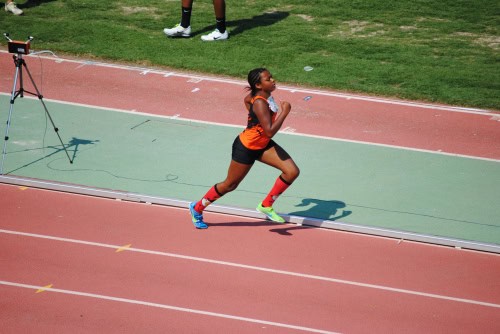 Female sprinter running on track during a track and field event.