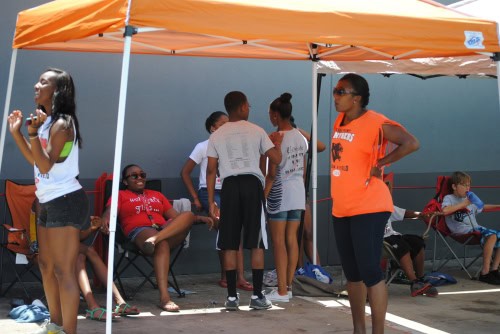 Panthers Elite Track & Field team members under orange canopy during outdoor event.