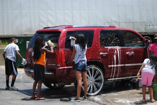 Kids washing a red SUV during a community event at Panthers Elite Track & Field Club.
