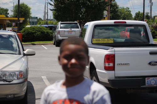 Young boy smiling in parking lot at Panthers Elite Track & Field Club event.