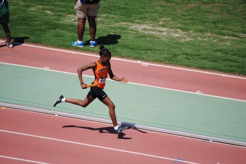 Female sprinter running on a track during a track and field event.