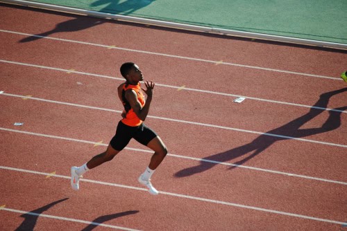 An energetic young athlete running on a track during a race.