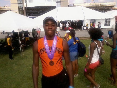 Athlete wearing orange uniform with medal at track event.
