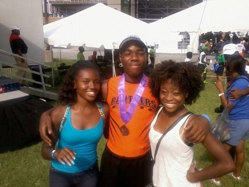 Three young athletes smiling, celebrating with medals at Panthers Elite Track & Field event.