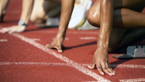 Fast sprinter at the starting line on a red track during a track and field event.