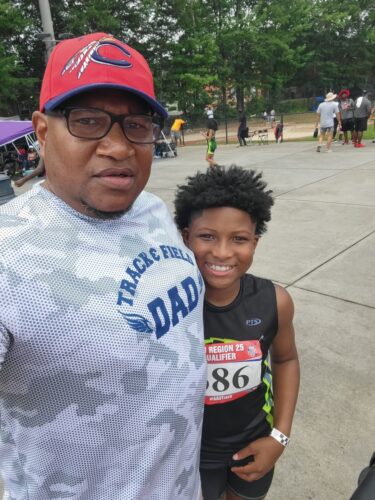 Athlete and coach at a track meet outdoors.