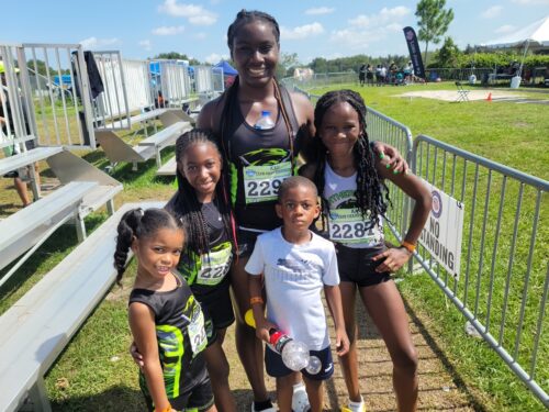 Group of young athletes with coach at track meet.