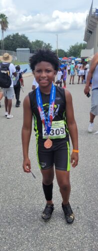 Young athlete with medal at track event, smiling after race.
