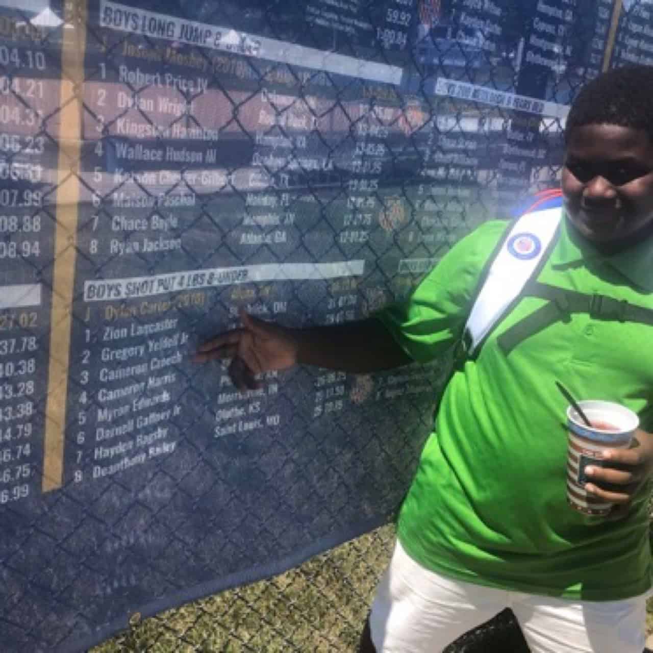 Young athlete pointing at race results board.