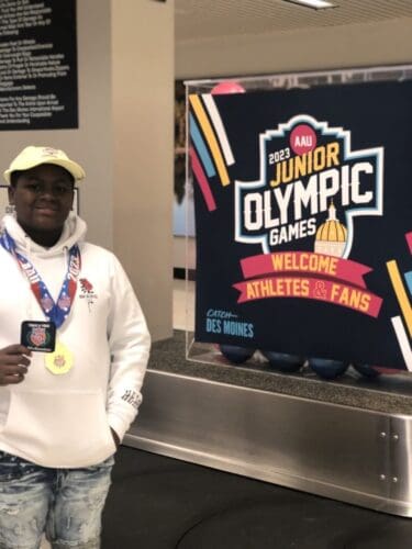 Young athlete holding medal at Junior Olympic Games 2023.