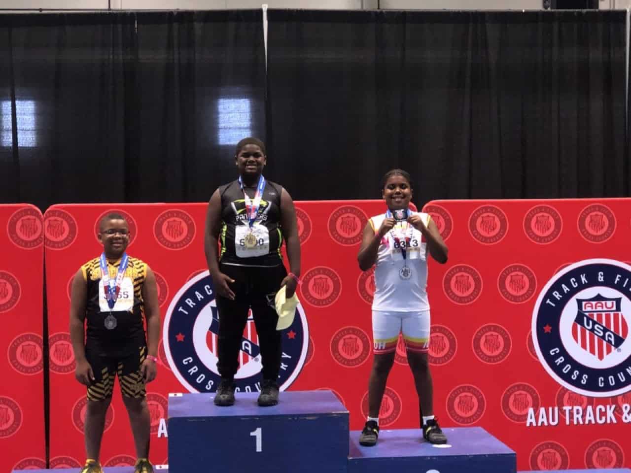 Youth track athletes on podium at AAU Cross Country meet.