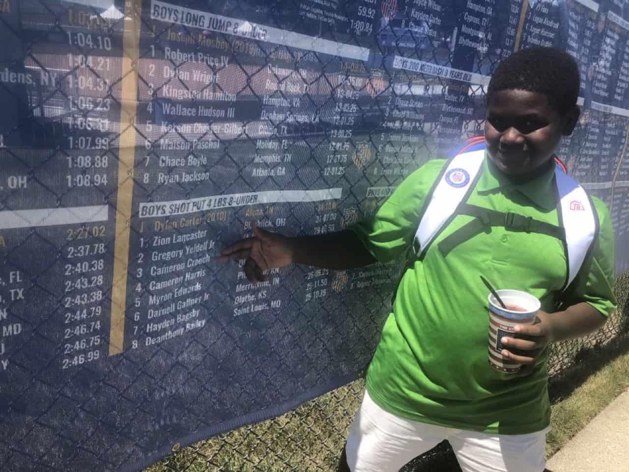 Young athlete pointing at track results board during meet.
