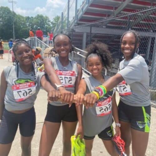 Group of young female athletes smiling at the track meet.