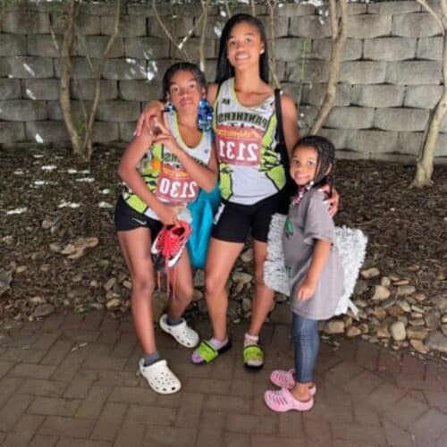 Group of young female athletes in track uniforms outdoors.