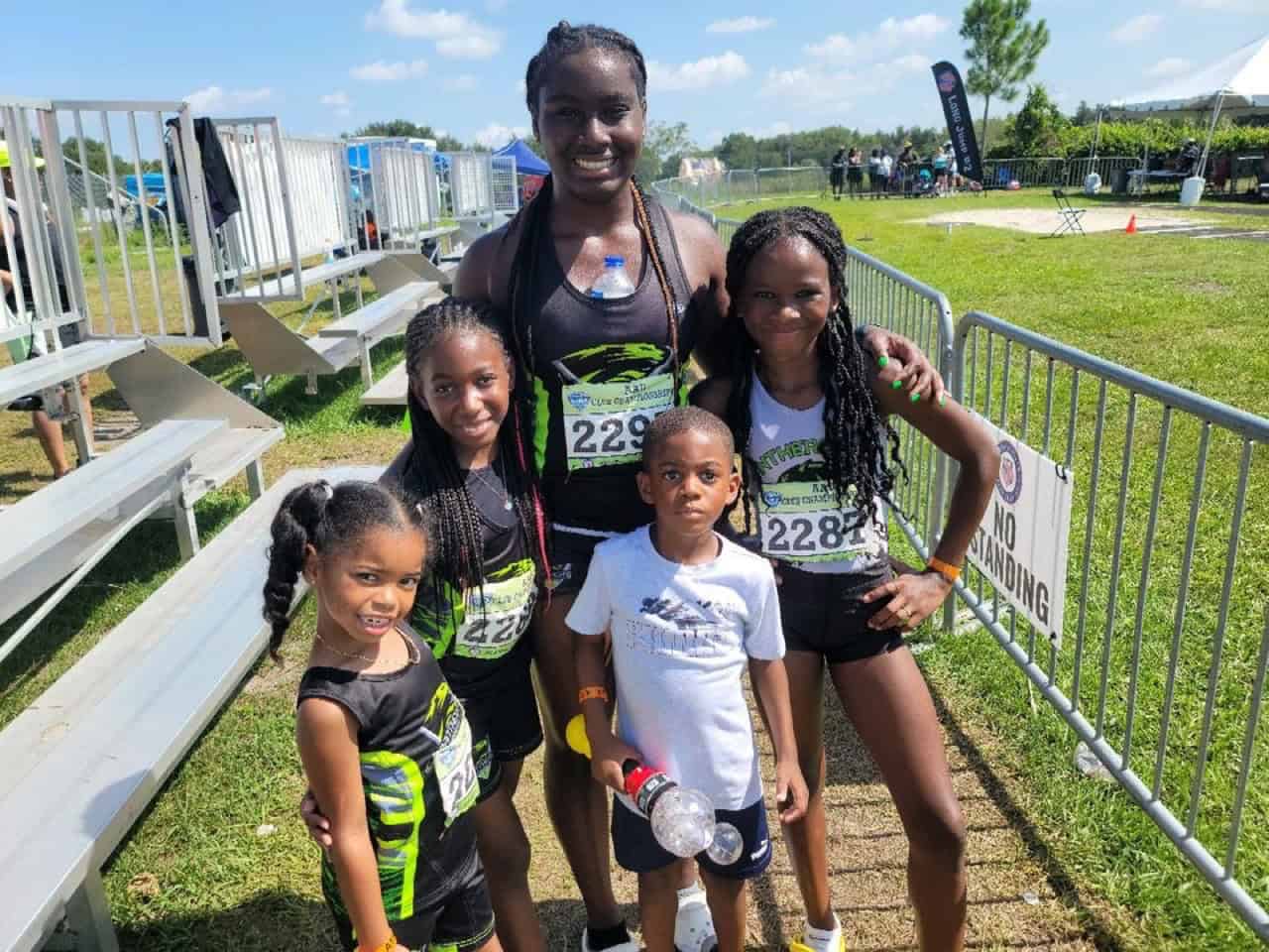 Group of young female athletes with coach at track event.
