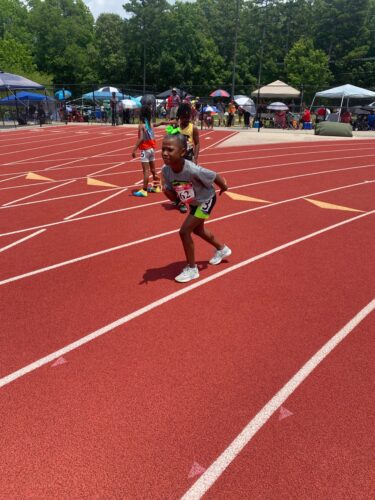 Young girl sprinting on a track during a track and field event.