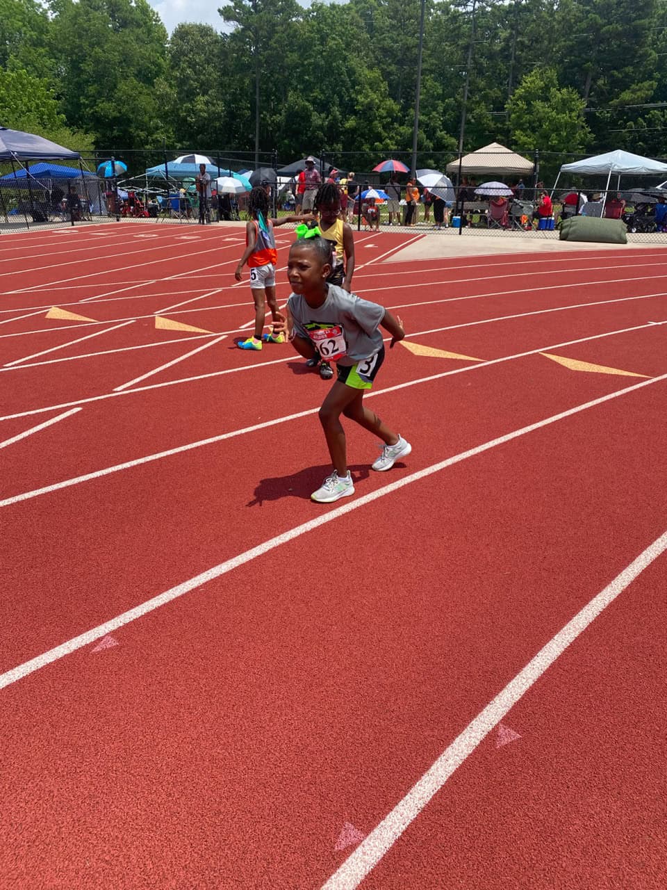 Young girl sprinting on a track during a track and field event.