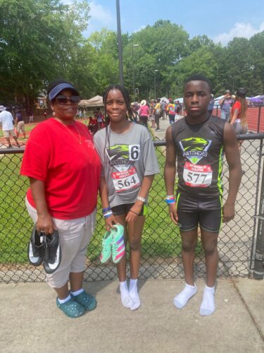 Panthers Elite track athletes with coach at outdoor meet.