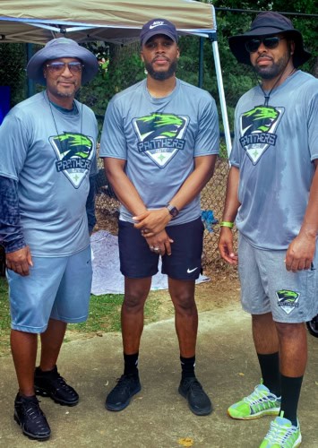 Panthers Elite Track & Field coaches at a meet, wearing team shirts and hats.