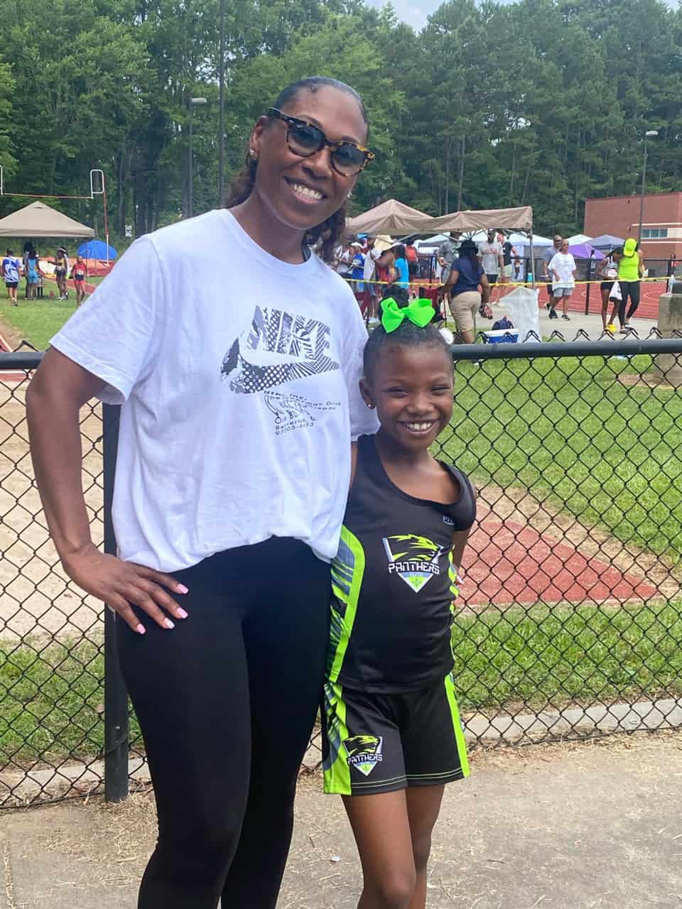 Coach and young athlete smiling at outdoor track and field event.