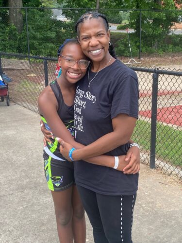 Young athlete and coach embracing after practice.