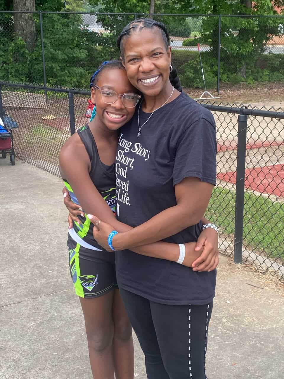 Young athlete and coach embracing after practice.