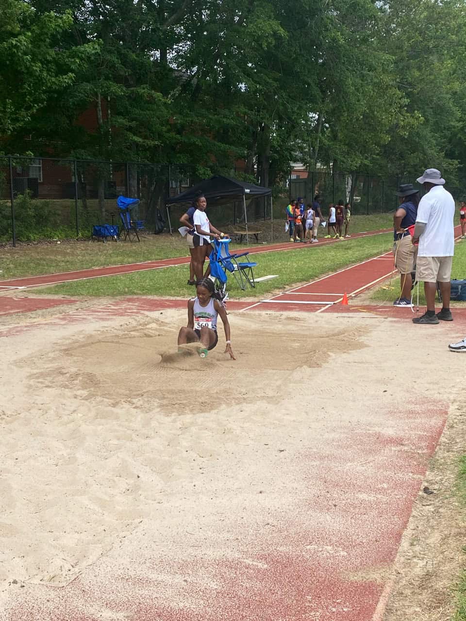 Young athlete jumping into sandpit during track and field event.