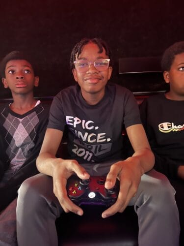 Young athletes playing video games at Panthers Elite Track & Field Club event.