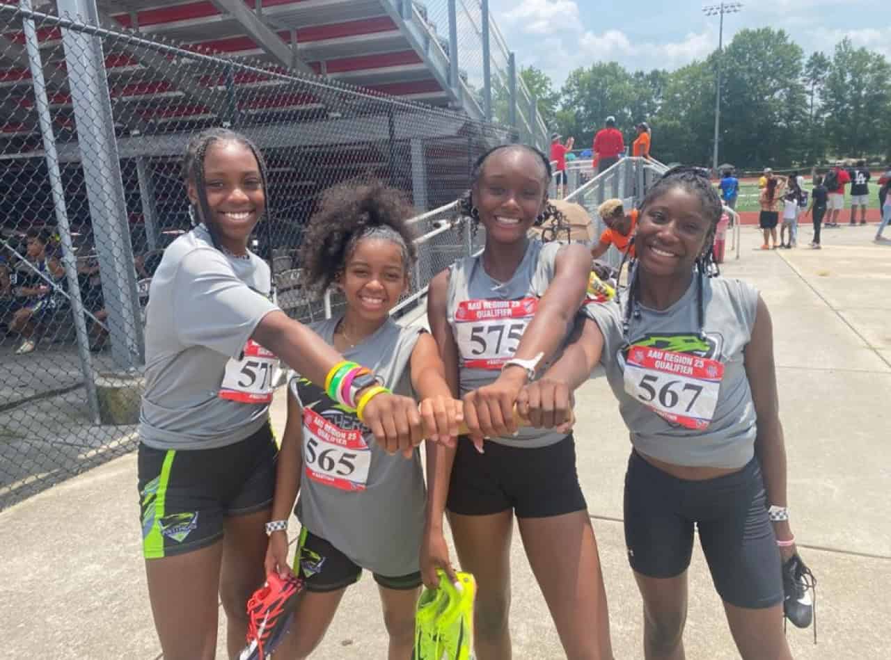 Group of young female athletes from Panthers Elite Track & Field Club smiling after a race.