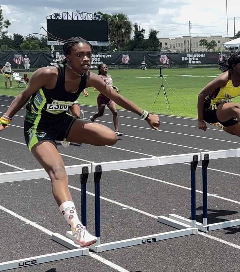 Fast female hurdler clearing a hurdle during a track and field race at Panthers Elite Track & Field.