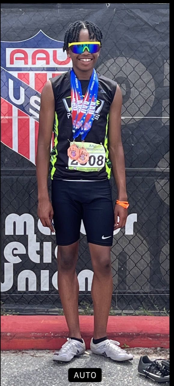 Elite track athlete wearing sunglasses and medals at a competition.