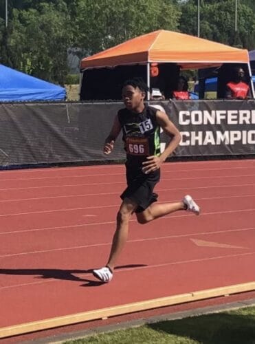 Athlete running on the track during a meet at Panthers Elite Track & Field Club.