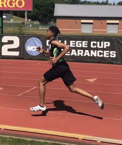 Young athlete sprinting on outdoor track during competition.