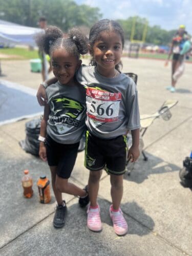 Two young girls smiling at the track meet.