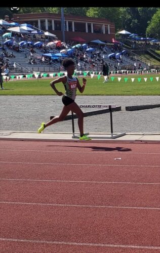Young female athlete competing in a track race at a stadium.
