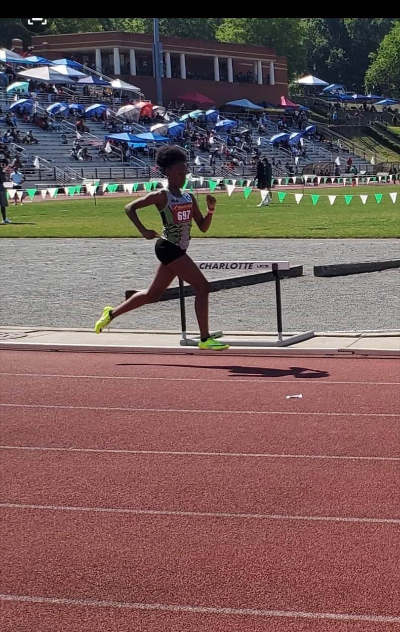 Young female athlete competing in a track race at a stadium.