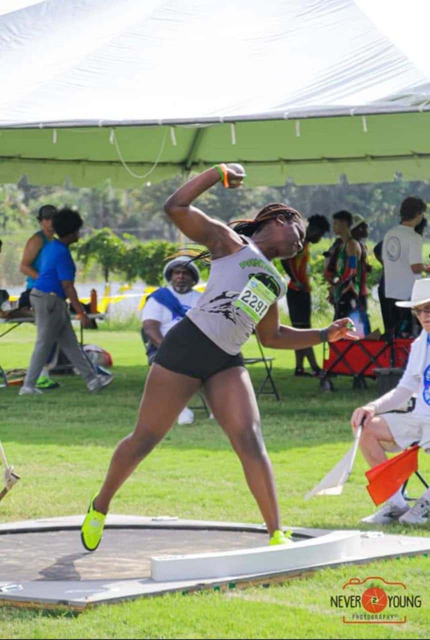 Female athlete in mid-throw at Panthers Elite Track & Field event outdoors.