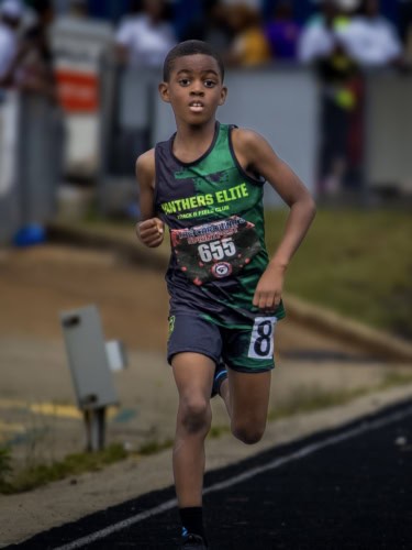 Young athlete running on track during a Panthers Elite meet.